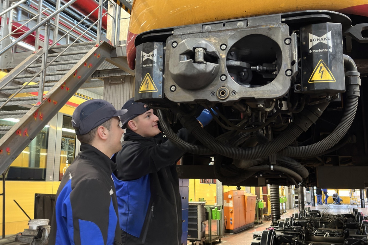 Zwei Duale Studenten arbeiten an der Rückseite einer Bahn.