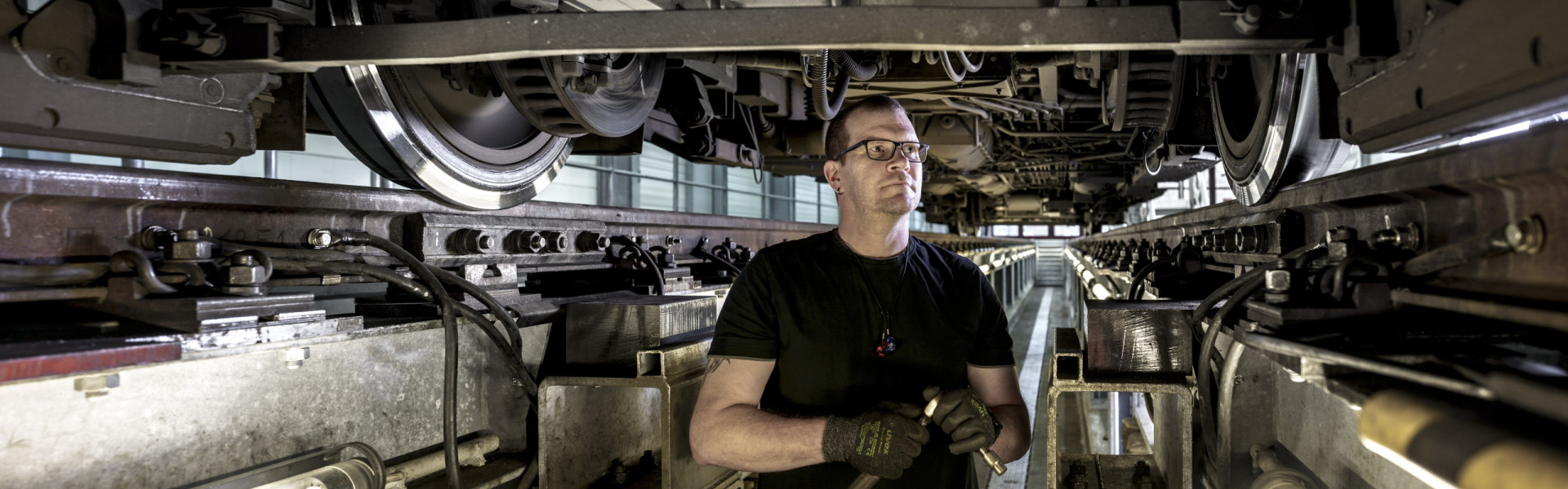 Ein Mitarbeiter aus der Werkstatt arbeitet unter einer Bahn.