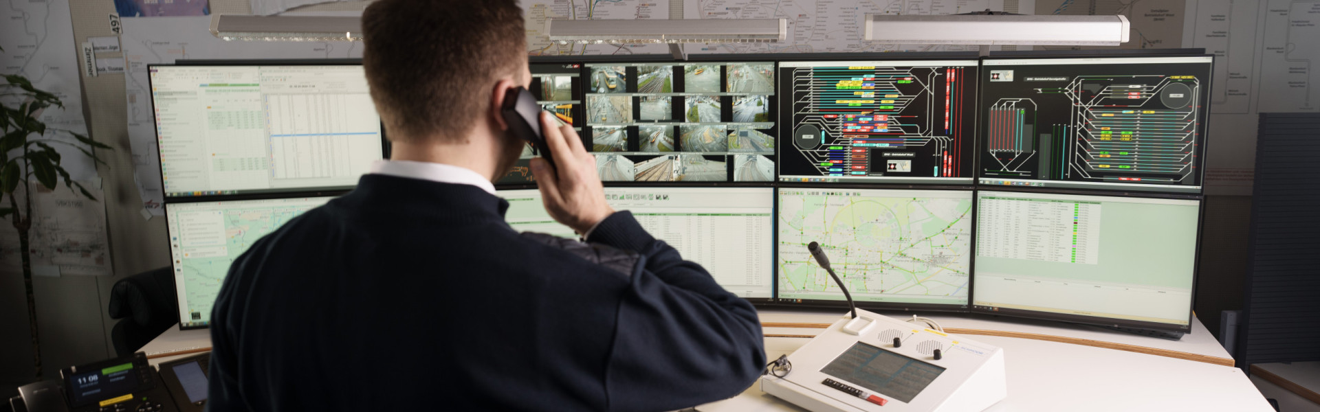 Ein Mitarbeiter der Leitstelle ist am Telefon und sieht auf die Monitore.