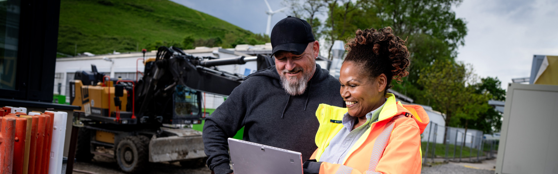 Eine Mitarbeiterin des Baus zeigt einem Kollegen etwas auf dem Tablett.